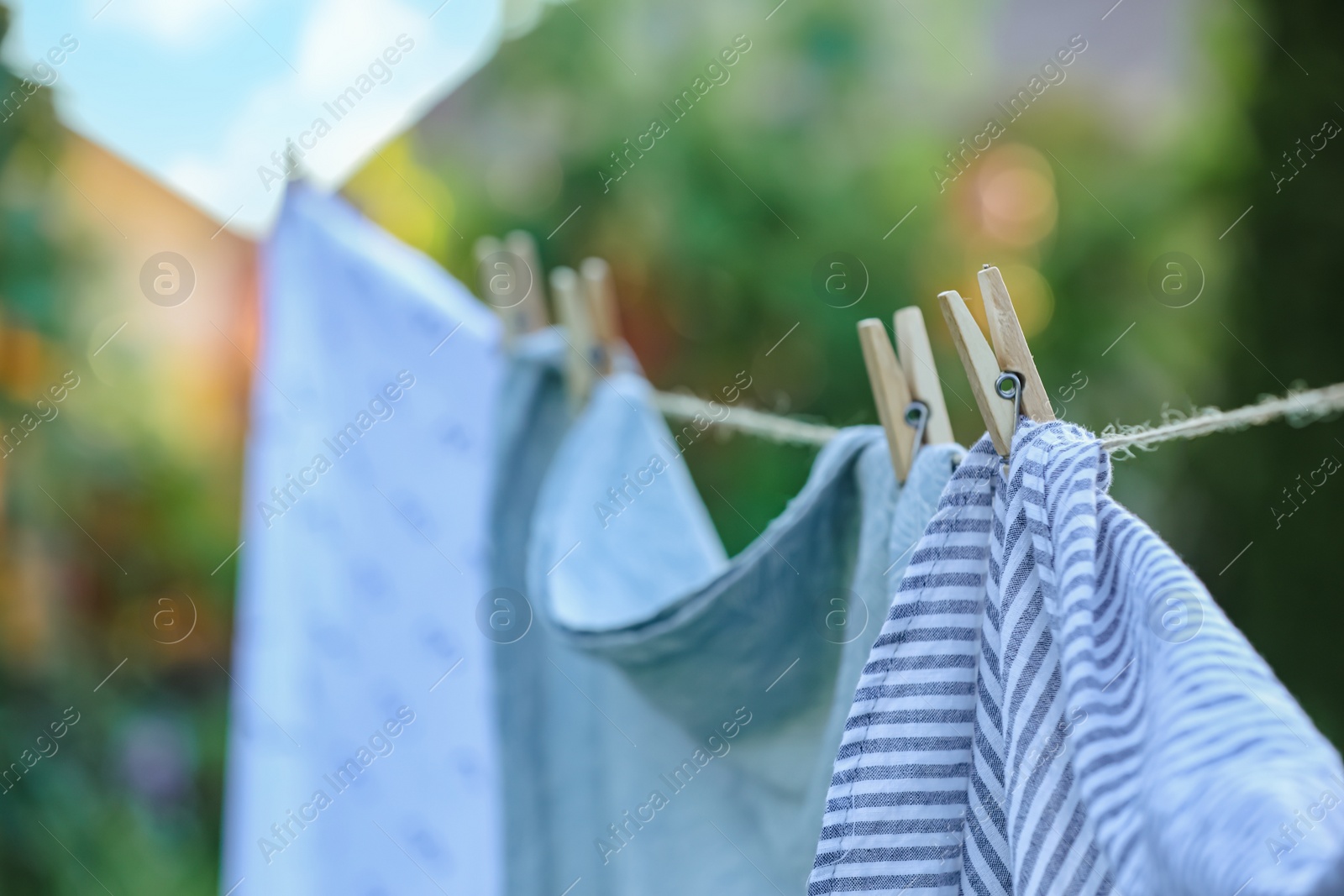 Photo of Washing line with drying shirts against blurred background, focus on clothespin