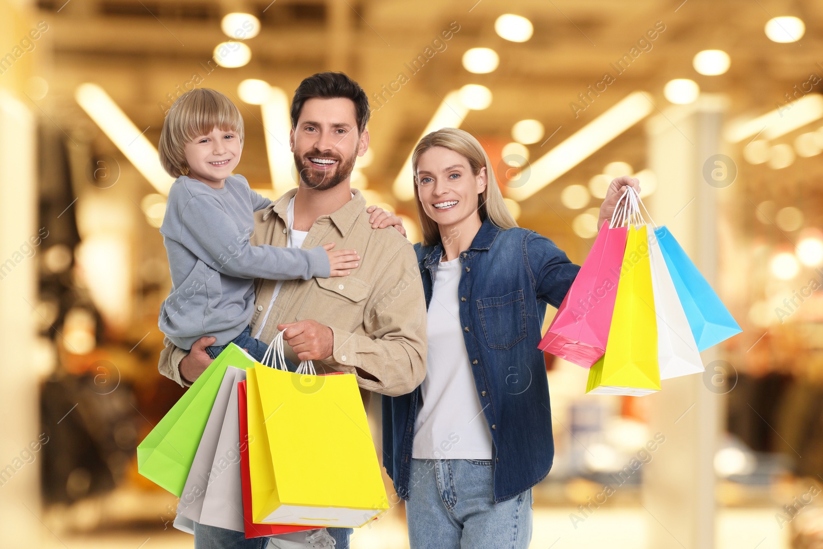 Image of Happy family with shopping bags walking in mall