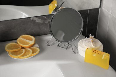 Photo of Lemon face wash. Fresh citrus fruits, personal care products and mirror on sink in bathroom