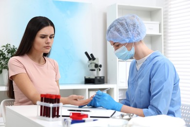 Photo of Laboratory testing. Doctor taking blood sample from patient at white table in hospital