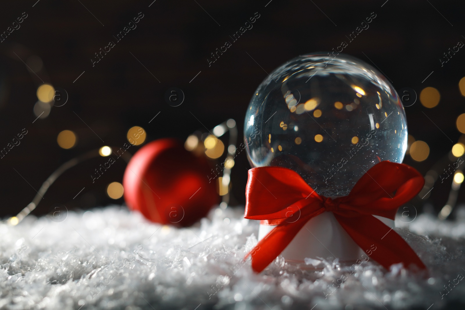 Photo of Christmas glass globe with artificial snow on blurred background. Space for text