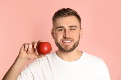 Photo of Young man with healthy teeth and apple on color background