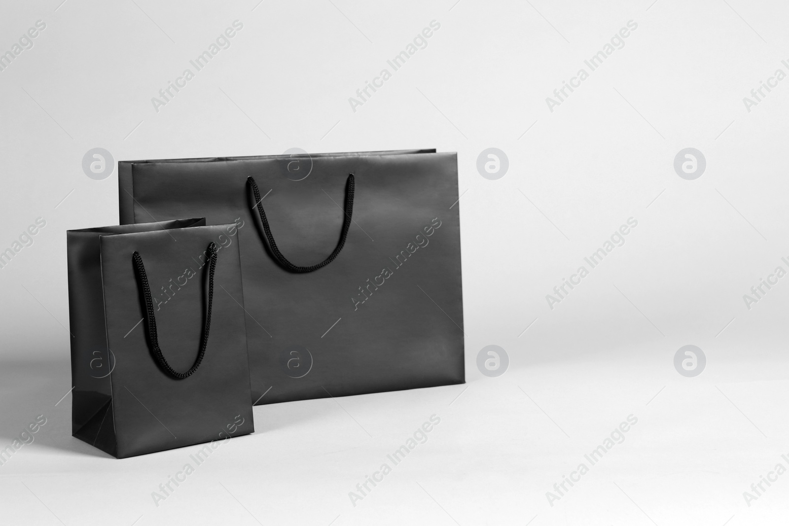 Photo of Two black paper shopping bags on grey background. Space for text