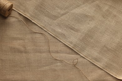 Photo of Spool of thread on burlap fabric, top view