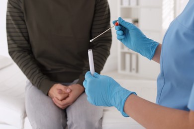 Photo of Doctor taking sample for STD testing from man in clinic, closeup