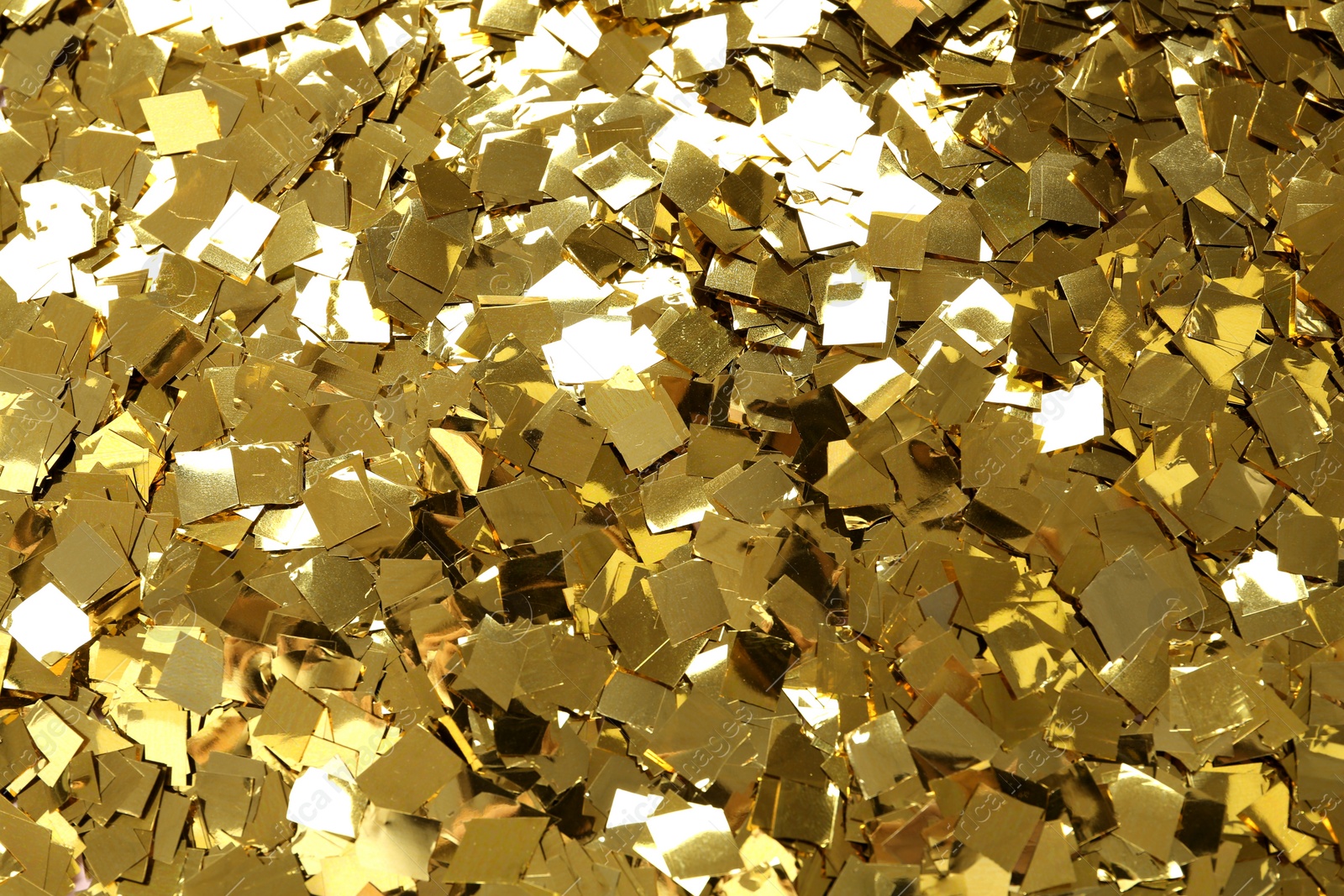 Photo of Bright golden confetti as background, top view