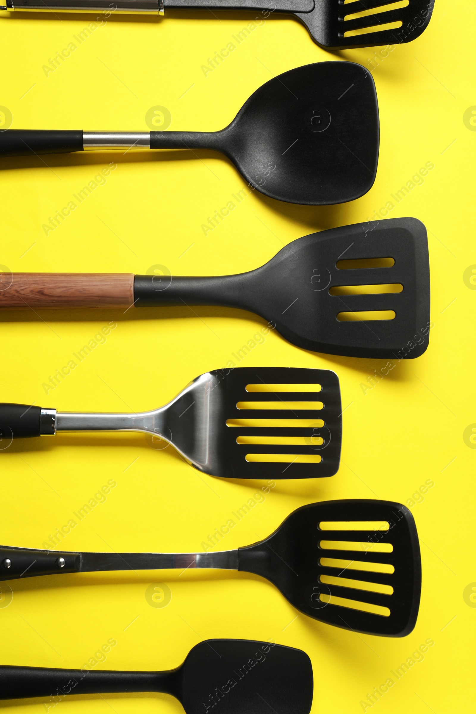 Photo of Different spatulas on yellow background, flat lay