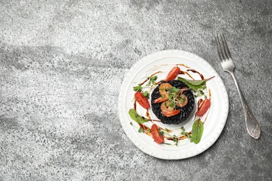 Delicious black risotto with seafood on grey table, flat lay. Space for text