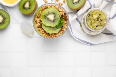 Delicious dessert with kiwi, muesli and fresh cut fruits on white table, flat lay. Space for text