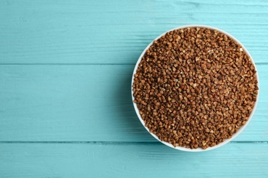 Photo of Buckwheat grains on light blue wooden table, top view. Space for text