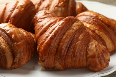 Plate with tasty croissants on table, closeup