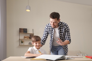 Photo of Dad helping his son with school assignment at home