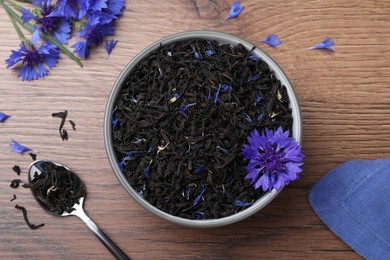 Photo of Dried cornflower tea and fresh flowers on wooden table, flat lay