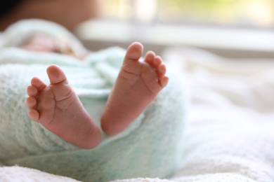 Newborn baby lying on white plaid, closeup of legs