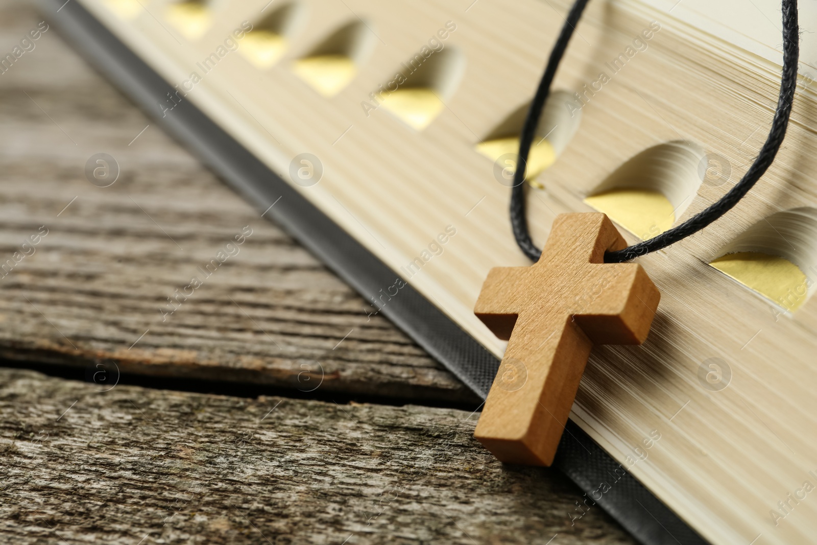 Photo of Christian cross and Bible on wooden table, closeup. Space for text