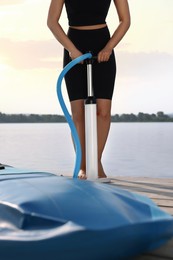 Woman pumping up SUP board on pier, closeup