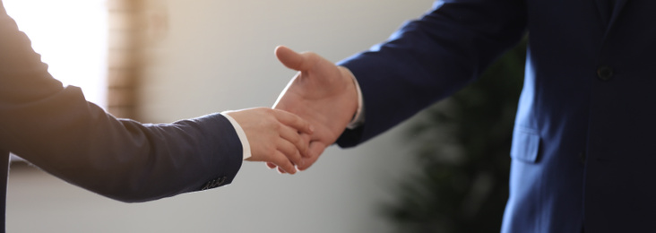 Image of Male lawyer shaking hands with client in office, closeup. Banner design