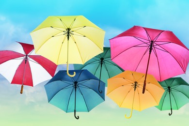 Image of Group of different colorful umbrellas against blue sky on sunny day