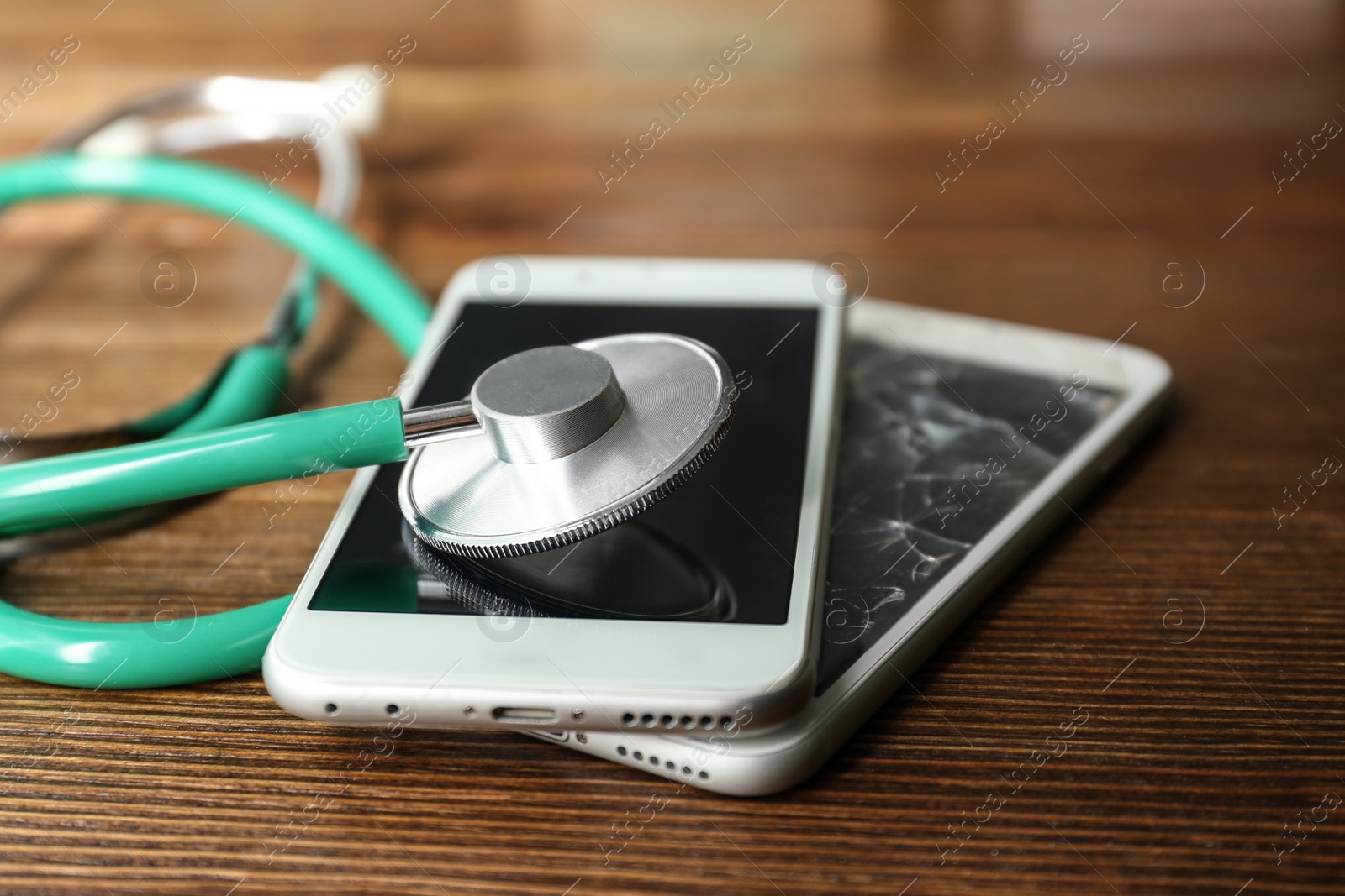 Photo of Smartphones and stethoscope on wooden table, closeup with space for text. Repairing service
