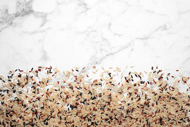 Photo of Mix of brown rice on marble table, top view. Space for text