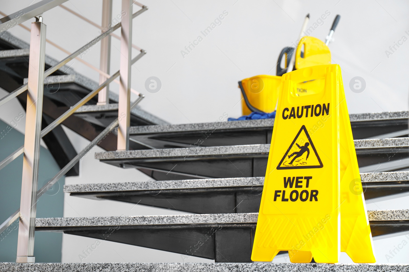 Photo of Safety sign with phrase Caution wet floor and mop bucket on stairs. Cleaning service