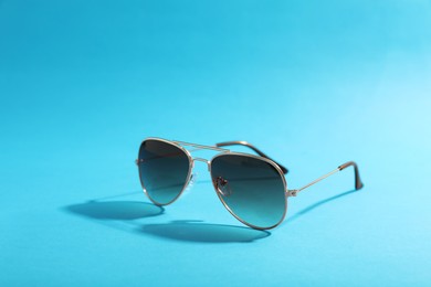 Stylish sunglasses on light blue background. Space for text