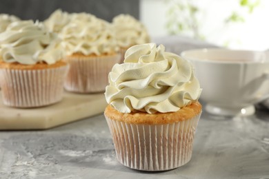 Photo of Tasty cupcakes with vanilla cream on grey table, closeup