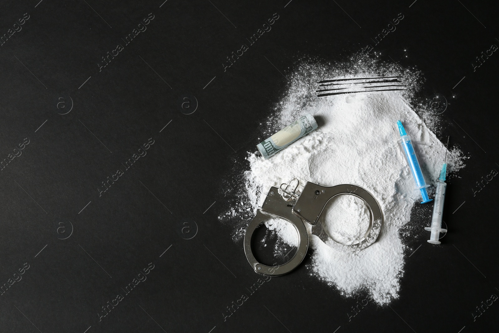 Photo of Composition with heap of cocaine, syringes and space for text on black background, top view