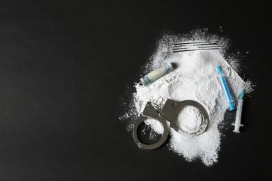 Photo of Composition with heap of cocaine, syringes and space for text on black background, top view