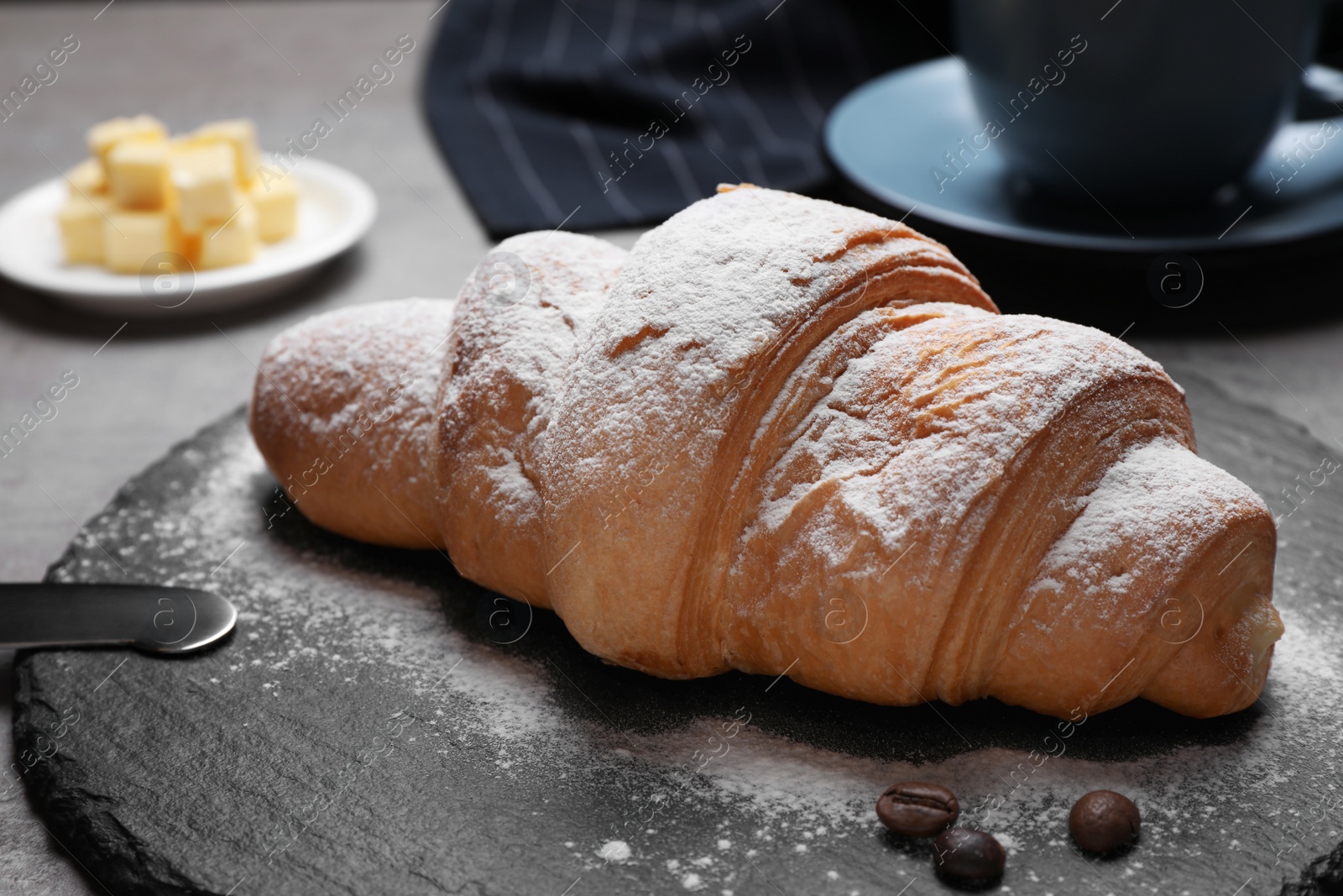 Photo of Tasty croissant with powdered sugar on table, closeup