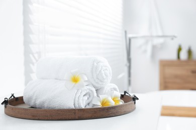 Photo of Tray with rolled bath towels on white table indoors. Space for text