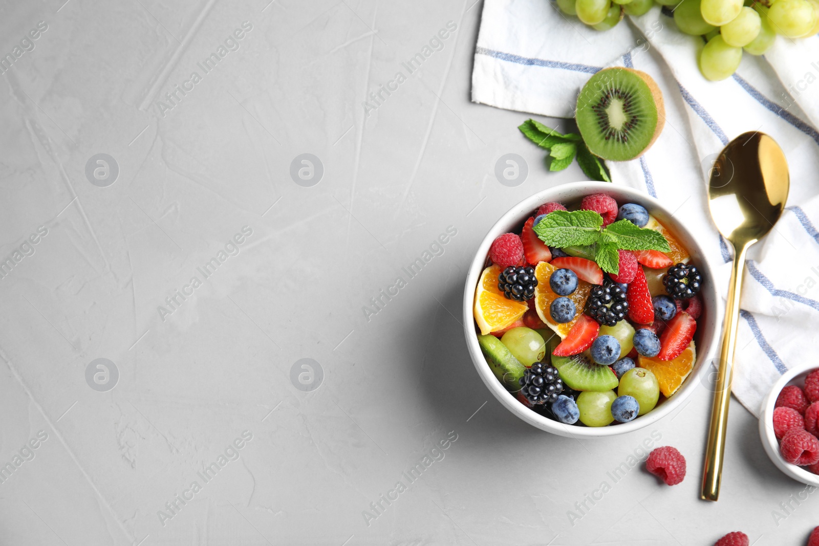 Photo of Fresh tasty fruit salad on grey table, flat lay. Space for text