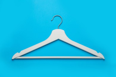 Empty wooden hanger on light blue background, top view