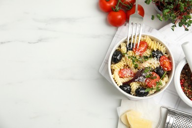 Photo of Bowl of delicious pasta with tomatoes, olives and cheese on white table, flat lay. Space for text