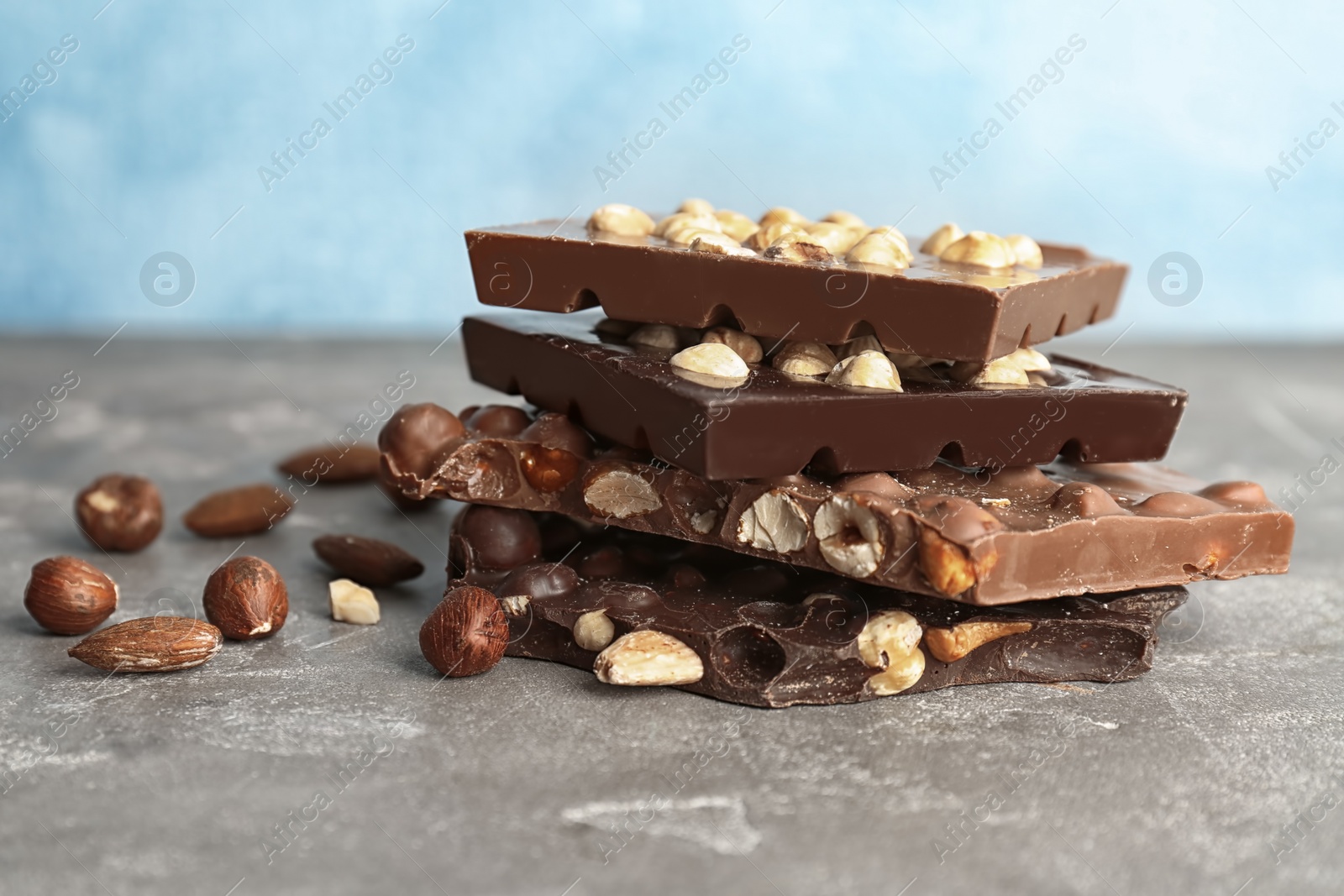 Photo of Delicious milk and dark chocolate bars with nuts on table