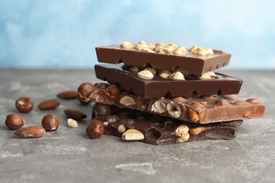 Photo of Delicious milk and dark chocolate bars with nuts on table