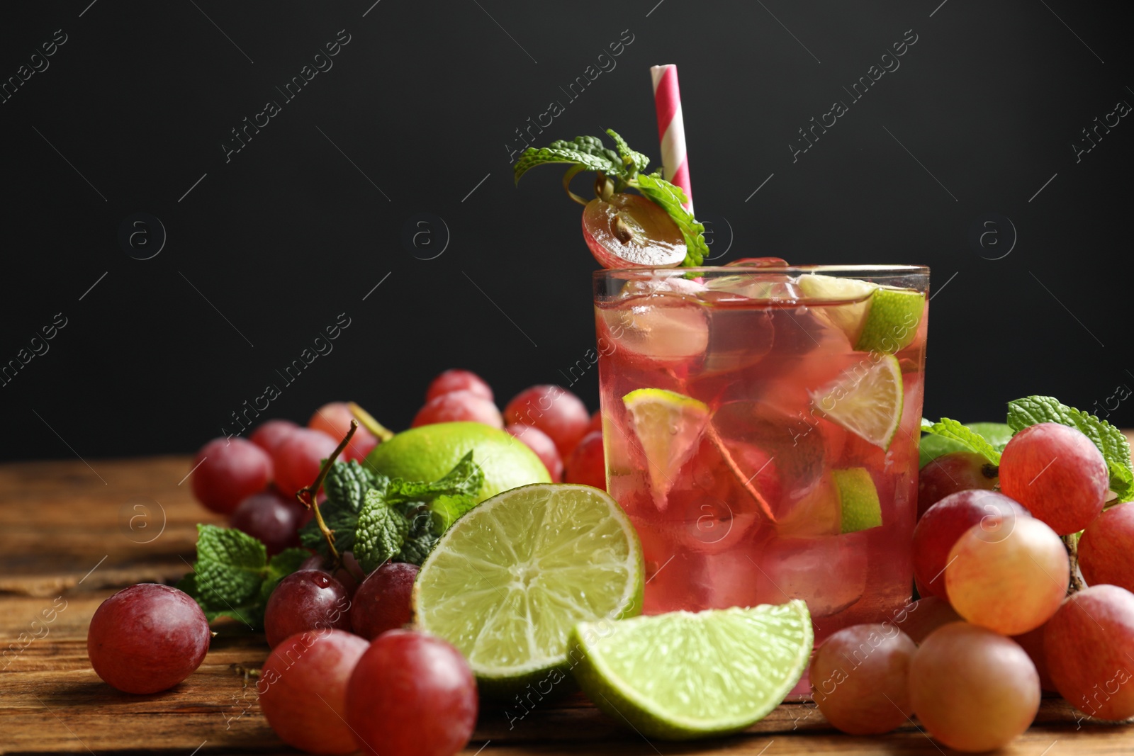 Photo of Soda water with grapes, ice, lime and mint on wooden table. Refreshing drink