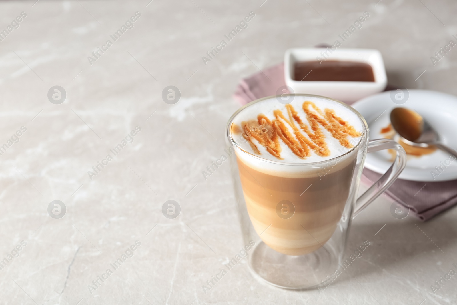 Photo of Glass of caramel macchiato on light table, space for text