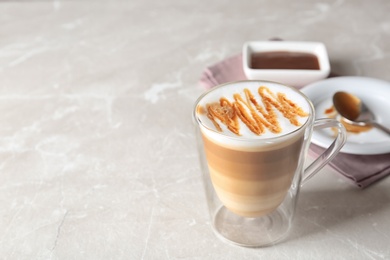 Glass of caramel macchiato on light table, space for text