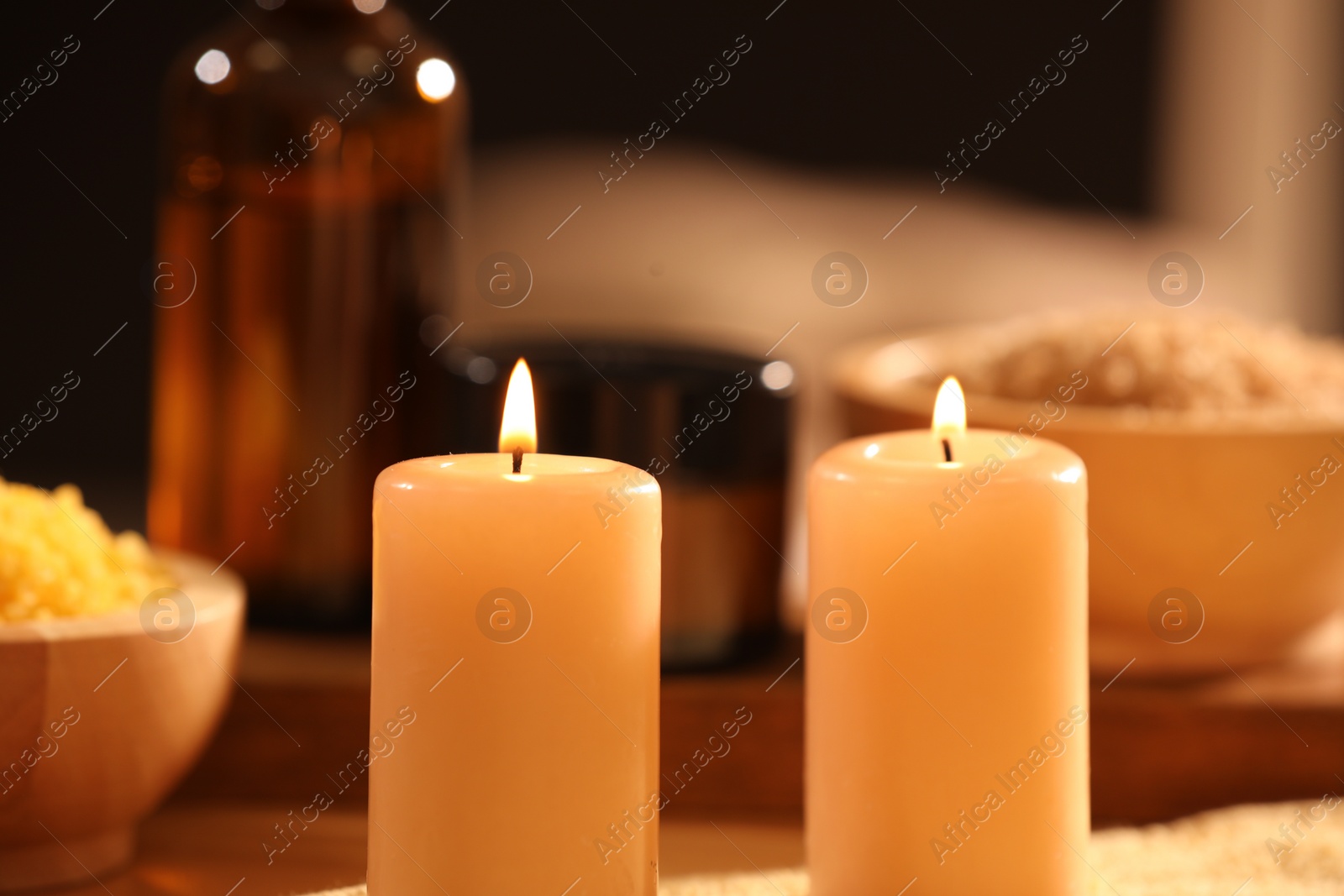 Photo of Spa composition with burning candles and personal care products on blurred background, closeup