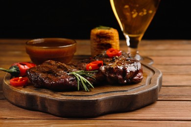 Glass of beer, delicious fried steak and sauce on wooden table