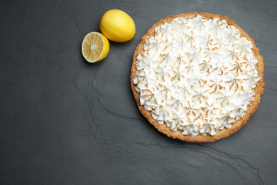 Flat lay composition with delicious lemon meringue pie on black table, space for text