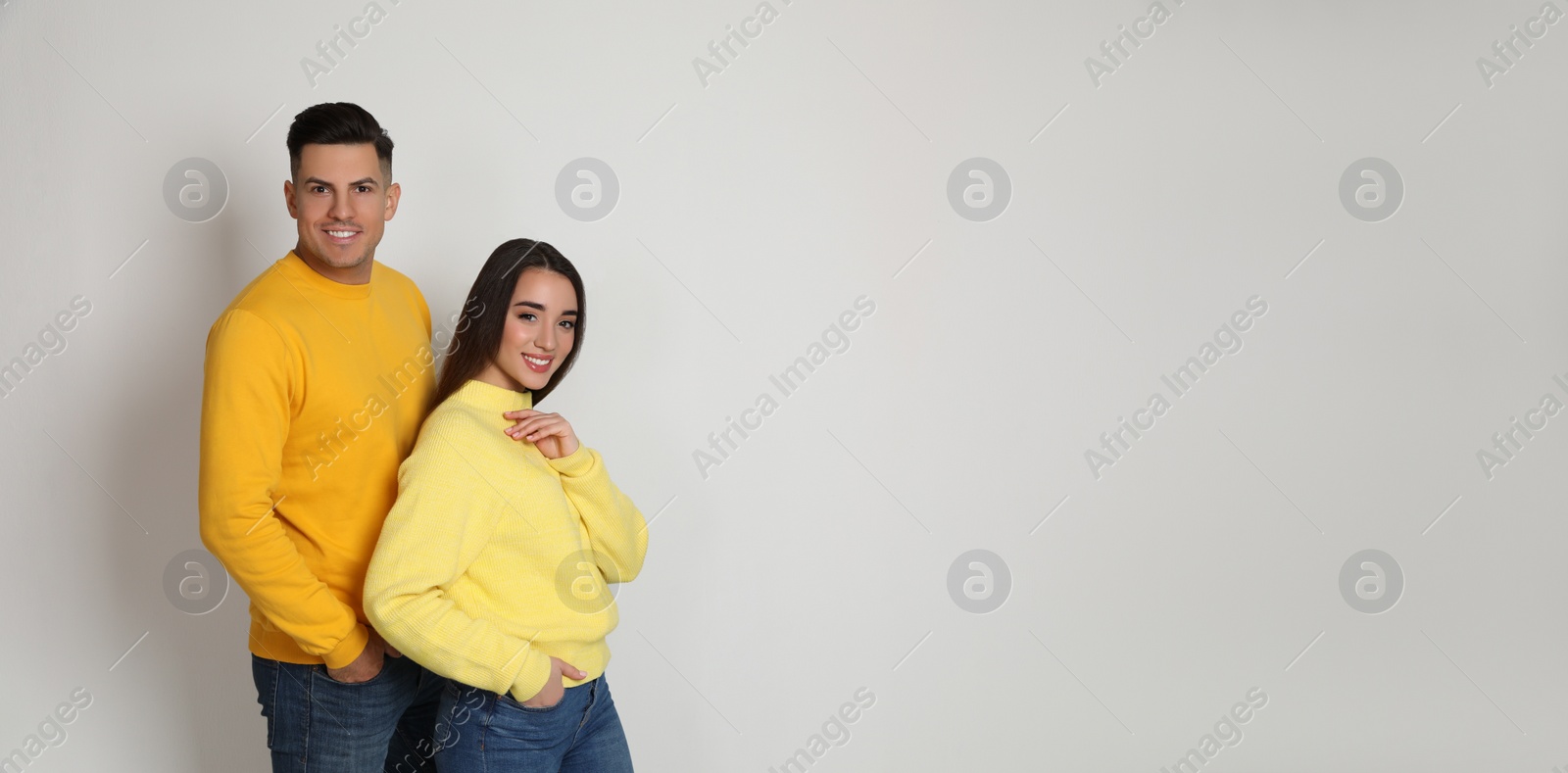 Photo of Happy couple wearing yellow warm sweaters on white background. Space for text