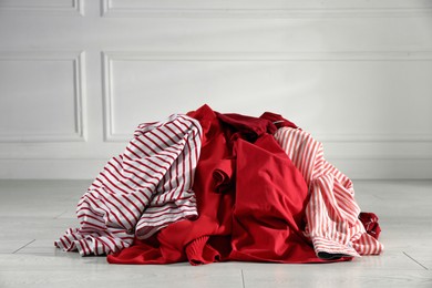 Photo of Pile of dirty clothes on floor near light wall indoors