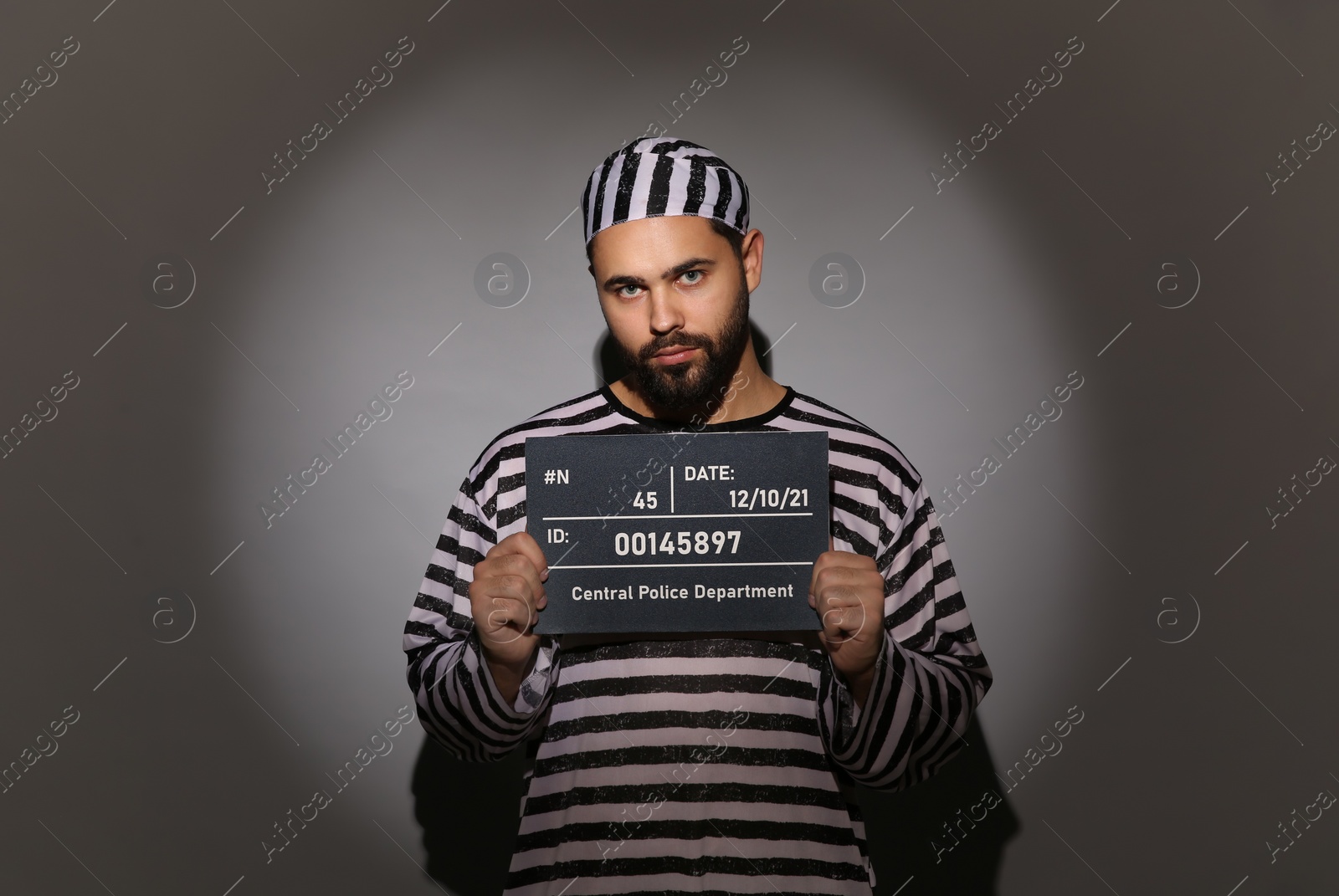 Photo of Prisoner in special uniform with mugshot letter board 
on grey background