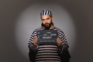 Photo of Prisoner in special uniform with mugshot letter board 
on grey background