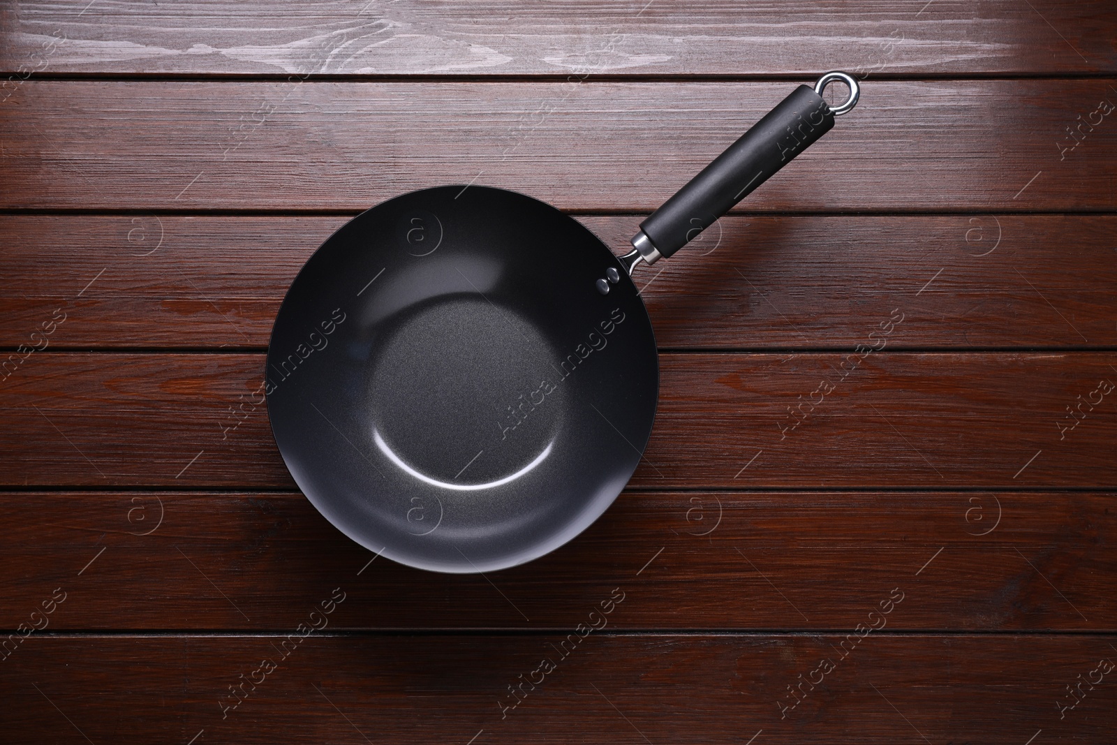 Photo of Empty iron wok on dark wooden table, top view. Chinese cookware