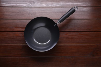 Empty iron wok on dark wooden table, top view. Chinese cookware