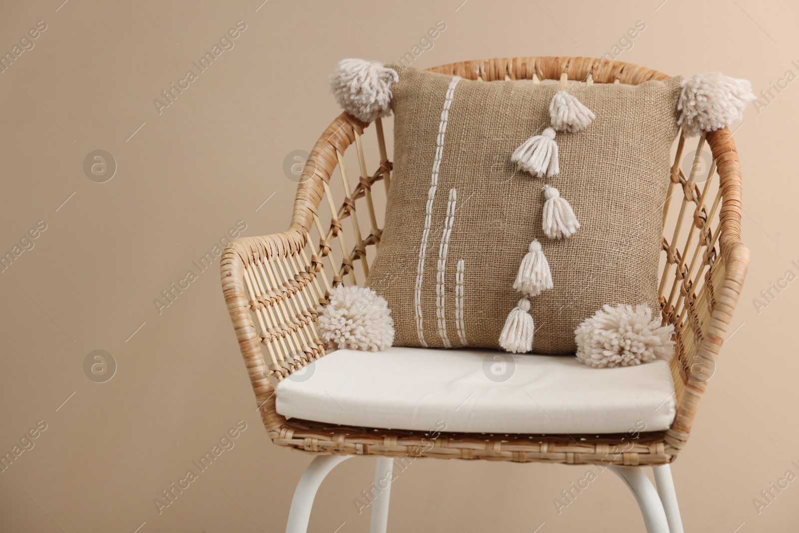 Photo of Stylish soft pillow on armchair near beige wall. Space for text