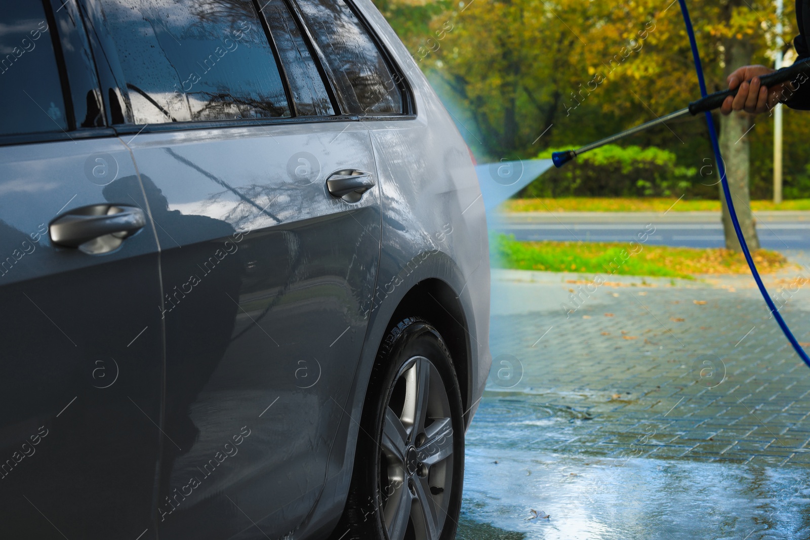 Photo of Man washing auto with high pressure water jet at outdoor car wash, closeup